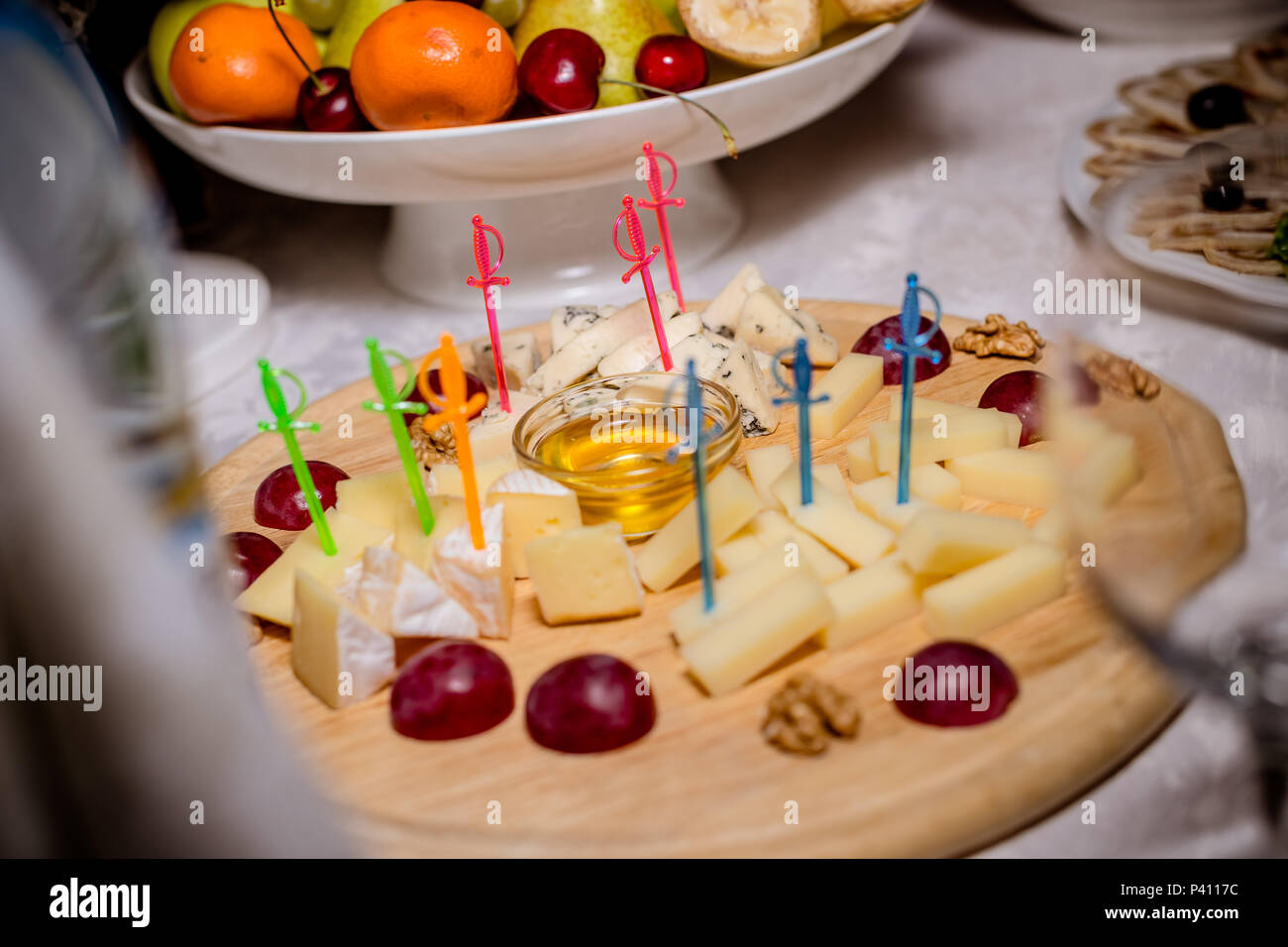 Still-leben Käseplatte mit Nüssen und Trauben. Käseplatte mit Nüssen und Honig serviert. Leckere kalte Vorspeise. Platte mit verschiedenen Sorten von Brie, Blau- und Parmesan. Buffet mit kalten Snacks Stockfoto