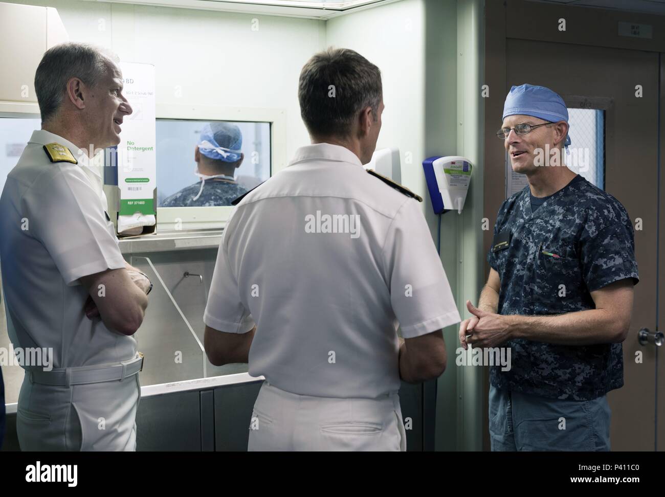 Foto von drei Marine Offiziere, eine getragen surgical Scrubs, sprechen mit jedem anderen an Bord des Hospital Ship USNS Mercy, in den Gewässern vor der Küste von Nha Trang, Vietnam, 23. Mai 2018. () Stockfoto