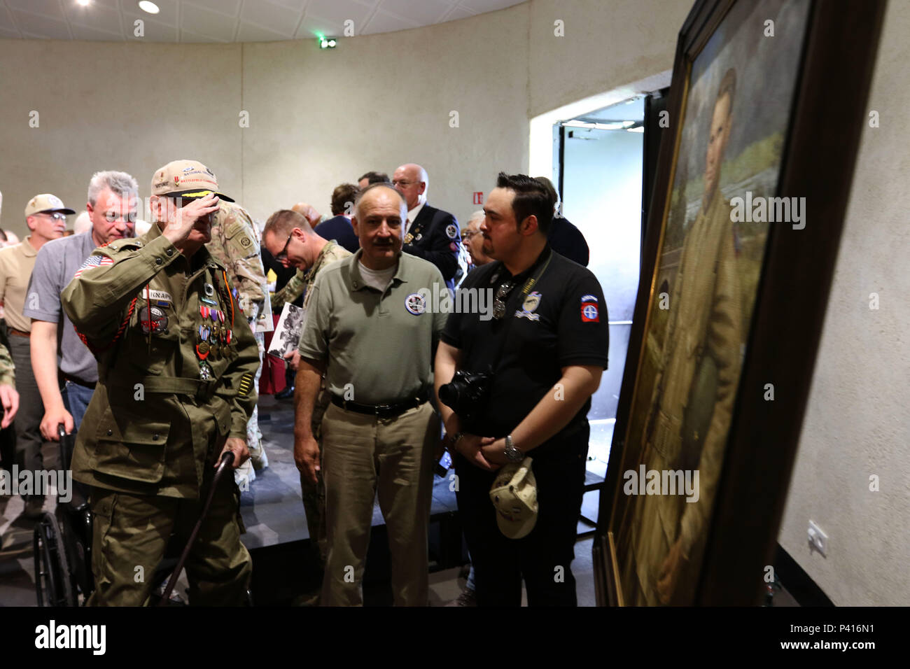 Ehemalige 1 Leutnant William Knapp und 82nd Airborne Division D-Day Veteran, steht von seinem Stuhl ein Gemälde von Generalleutnant James Gavin während der Enthüllung des Portrait an das Airborne Museum in Sainte-Mere-Eglise, Frankreich zu begrüssen. Das Portrait, im Auftrag der Leitung und Chloe Gavin, und von James Crowley gemalt vertreten ihren Vater an seinem besten, mit einem Gewehr in der einen Hand und den Helm in einer anderen, als er über seine geliebte Fallschirmjäger beobachtet. Das Gemälde wurde auf das Airborne Museum als Teil der D-Day 72 Gedenkfeiern gespendet. (U.S. Armee Foto vom Kapitän Joe Bush) Stockfoto