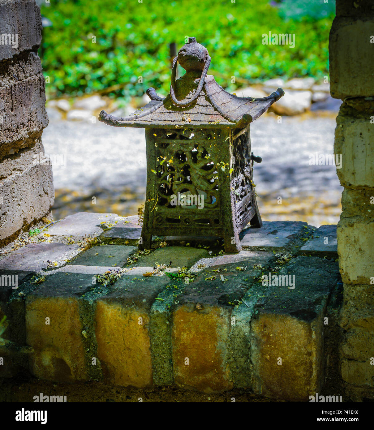 Alte Japanische Eisen Laterne sitzt auf alten Mauer im Garten Stockfoto