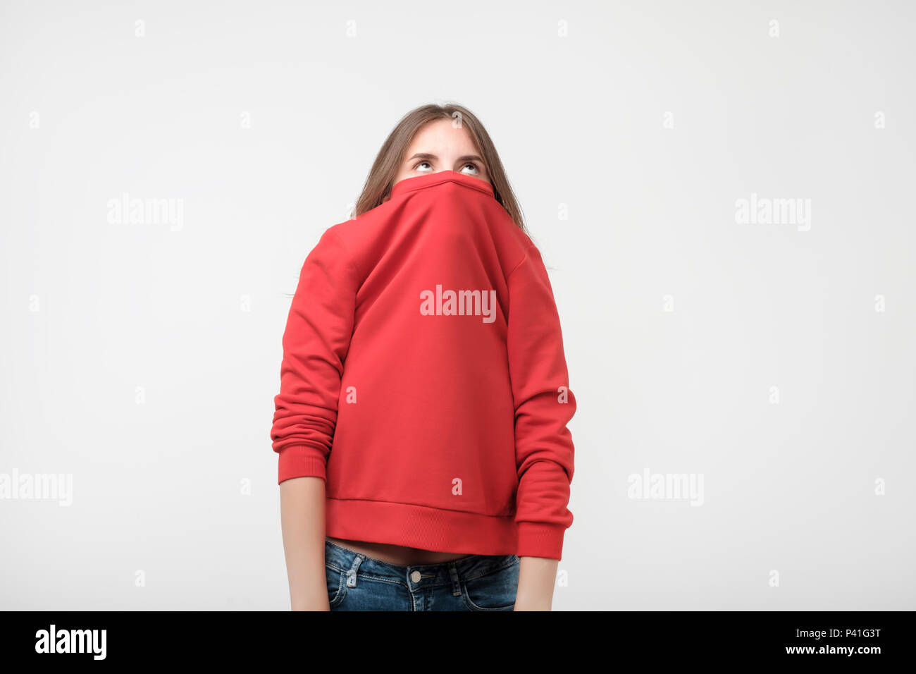 Ein Mädchen mit einer sozialen Phobie verbirgt ihr Gesicht in einen Pullover. Sie schaut die Kamera Angst Stockfoto