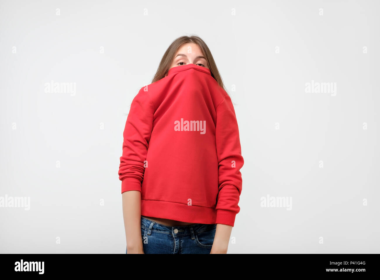 Ein Mädchen mit einer sozialen Phobie verbirgt ihr Gesicht in einen Pullover. Sie schaut die Kamera Angst Stockfoto