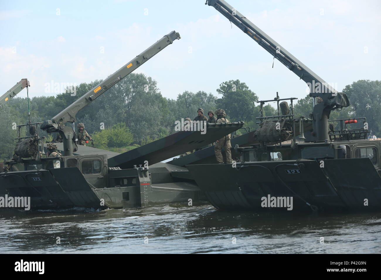 Gemeinsame Kräfte eine Brücke über M 3 amphibische Rigs zu ermöglichen einen Konvoi von M1126 Streikenden in Chelmno, Polen zu konstruieren. Juni 8. 2016 Anakanda ist ein polnisch-geführten multinationalen Übung, die in Polen von Juni 7-17. Die Übung bezieht mehr als 25.000 Teilnehmer aus mehr als 20 Ländern. (U.S. Armee Foto von SPC. Andrew Miller/Freigegeben) Stockfoto