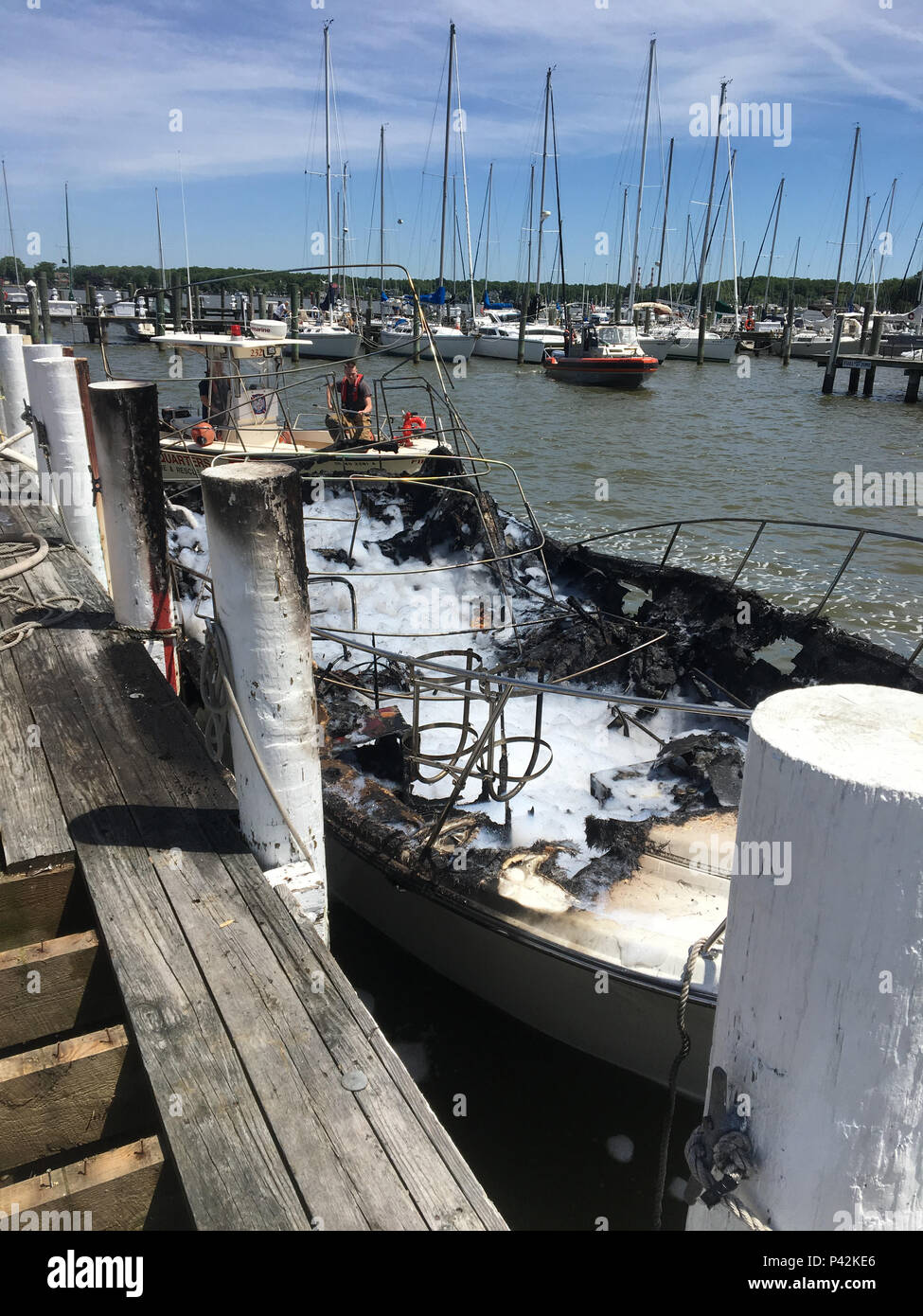 Hier sehen Sie ein beschädigtes Boot von einem Boot aus Feuer an der Pier von bowley's Marina in der Galloway Creek in der Nähe von nahen Fluss, Maryland, Freitag, 18.06.10, 2016. Baltimore County Feuerwehr löschte den Brand, und Rettungsdiensten transportiert zwei Personen Bayview Burn Center. (U.S. Coast Guard Foto von Petty Officer 2nd Çlass Johannes Sacino) Stockfoto