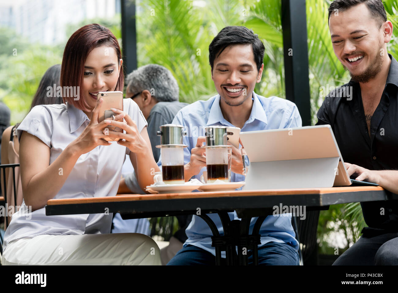 Freunden über Geräte, die mit dem Wlan eines modernen Coffee Shop angeschlossen Stockfoto