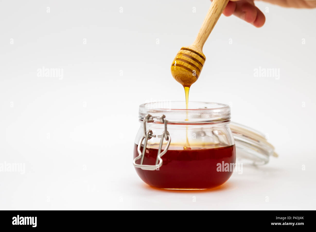 Hand mit einem honig Tropfer auf weißem Hintergrund. Essen Konzept. Stockfoto