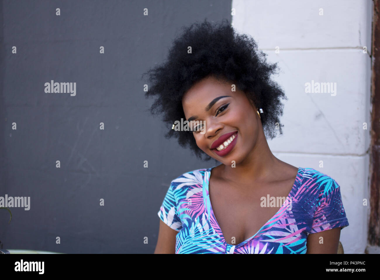 Eine afrikanische Frau Modell stellt neben eine dunkel kontrastiert Wand Stockfoto