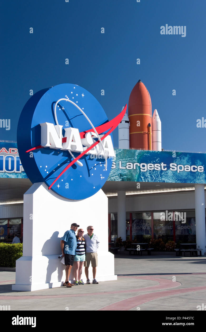 Touristen posieren für Fotos neben einem großen NASA-Logo außerhalb der Besucher des NASA Kennedy Space Center, Florida Komplex. Stockfoto