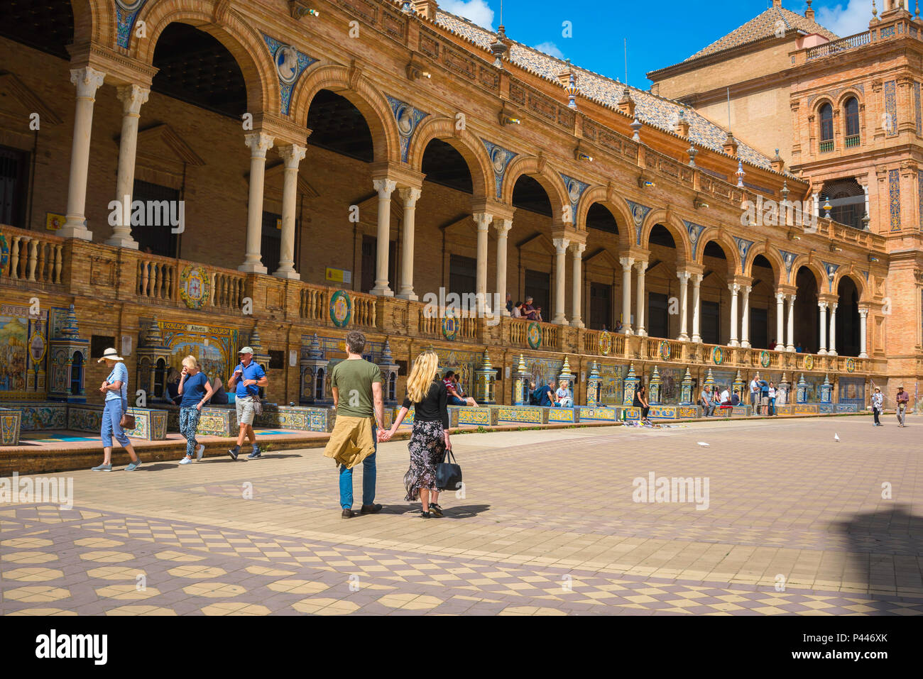 Reisen Sie nach Spanien, Blick auf ein junges Touristenpaar, das an einem Sommernachmittag an einer großen Kolonnade auf der Plaza de Espana vorbeigeht, Sevilla, Andalusien, Spanien. Stockfoto