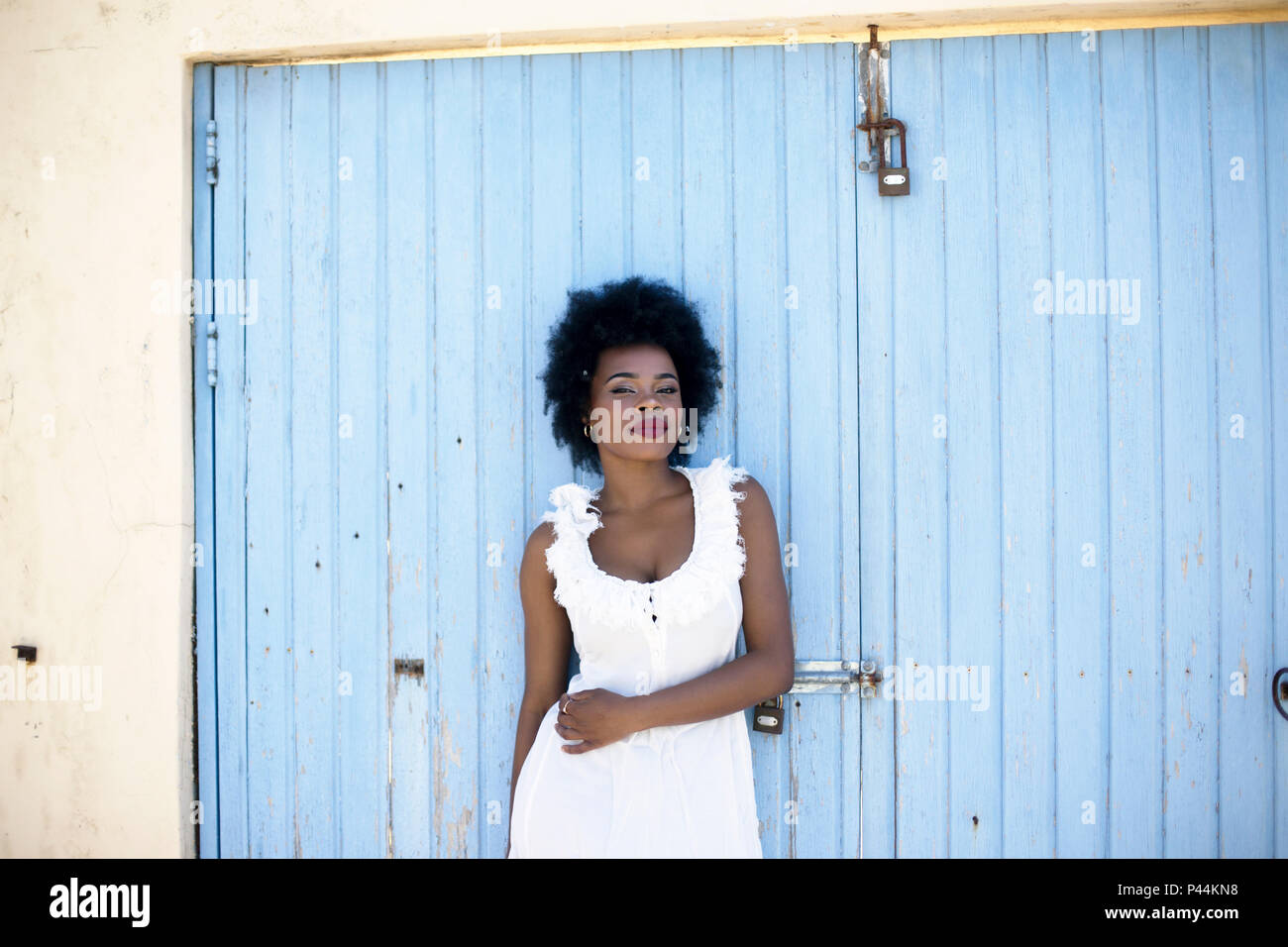 Eine junge südafrikanische Modell lehnt sich gegen ein Baby blaue Tür lackiert Stockfoto