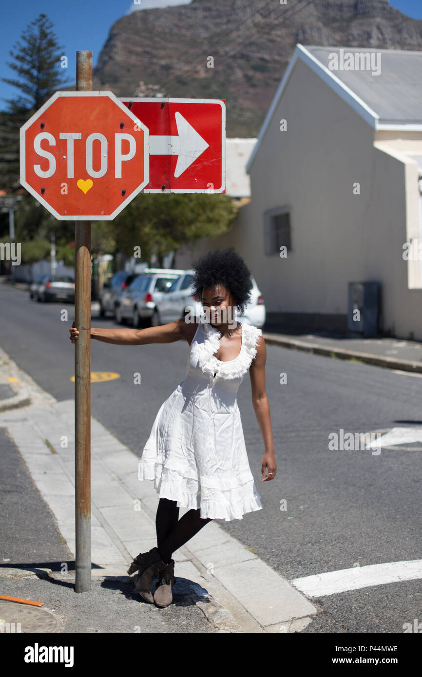 Ein junges Modell wirft, während Sie auf die Pole der ein Straßenschild auf einem Gehsteig Stockfoto