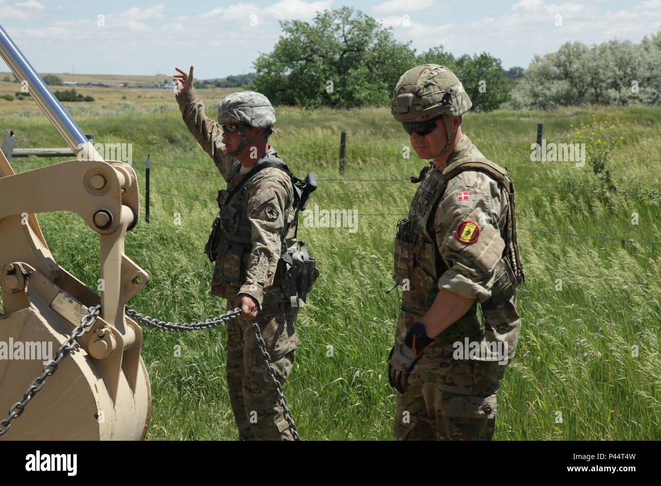 Us-Armee Sgt. Jed Laber und Overkonstabel af 1. Grad (Lance Cpl.) Hans Jacobsen mit der 3 Bauunternehmen, Dänemark Armee, die Bewegung auf die Betreiber von einer hohen Mobilität Ingenieur Hydraulikbagger (HMME) während des Ausbaus in einer Vieh reiben an Orman Damm in Unterstützung der Goldenen Coyote Übung, Belle Fourche, S.D., 13. Juni 2016. Die goldenen Coyote Übung ist eine dreiphasige, Szenario-driven Übung in den Black Hills von South Dakota und Wyoming, mit dem Kommandanten auf der Mission wesentliche Anforderungen der Aufgabe, Krieger Aufgaben und Übungen zu konzentrieren. (U.S. Armee Foto von Sgt. 1. Klasse Hor Stockfoto