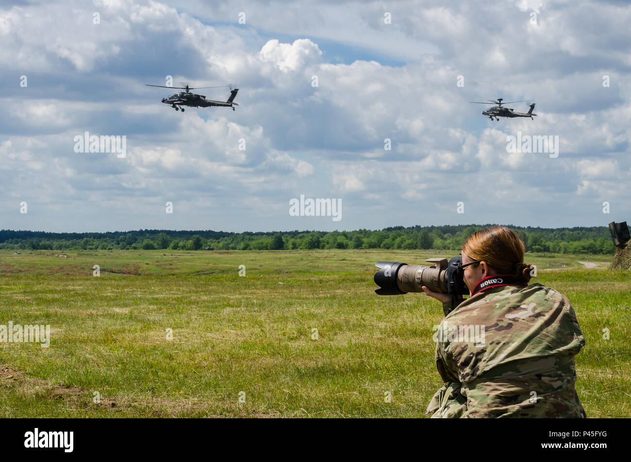 Us-Armee Sgt. Ashley Marmor, eine Bekämpfung der Dokumentation und Produktion Spezialist, nimmt sie Aufnahme, wie die US-Armee AH-64 Kampfhubschrauber während einer live Demonstration am 16. Juni 2016 Overhead fliegen, an der Drawsko Pomorski Training Area in Polen. Eine Pressekonferenz und die Live-demonstration präsentiert die gemeinsamen Anstrengungen der multinationalen Streitkräfte während der Übung Anakonda 2016. Die Polnisch-led-Übung ist eine gemeinsame Aus- und Fortbildung, um die Interoperabilität, die für den Ausbau und die Stärkung der Bande zwischen den alliierten Nationen und Partner, Gewährleistung der kollektiven Sicherheit und Frieden in der Region. Stockfoto