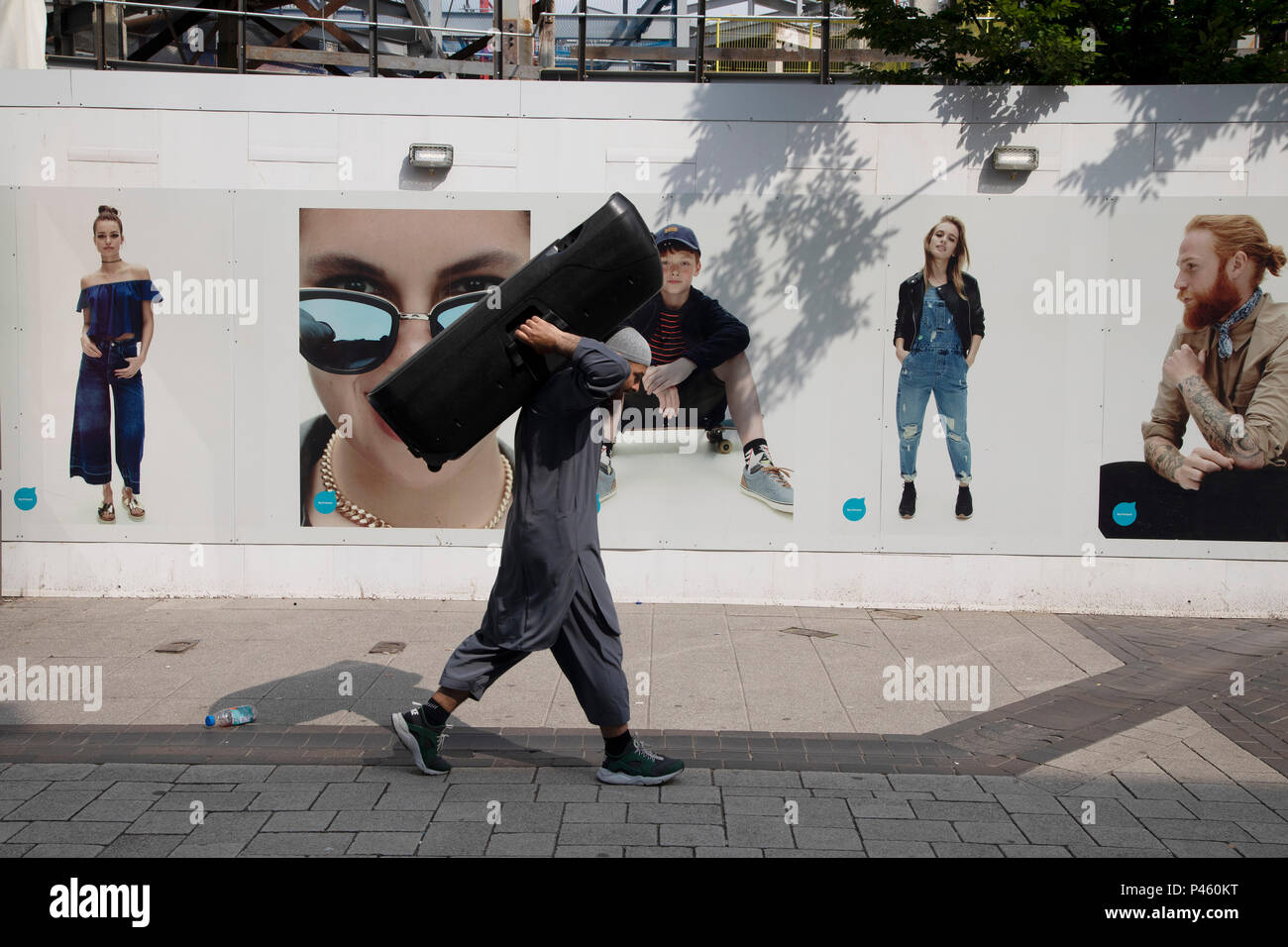 Leute einkaufen zu Fuß vorbei an einer Reihe von Postern für Primark, andere menschliche Figuren in einer seltsamen nebeneinander in Birmingham, Vereinigtes Königreich. Stockfoto