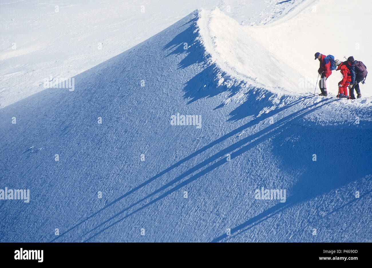 Eine Gruppe von drei Bergsteiger über den Rand eines steilen Abgrund auf der Aiguille de Midi in den Französischen Alpen suchen Stockfoto