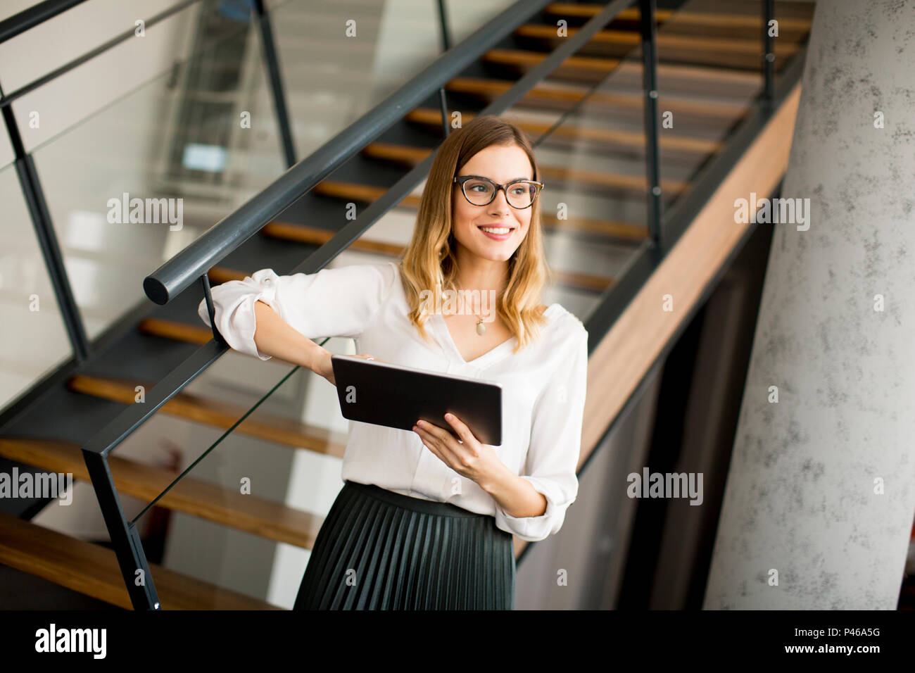 Junge attraktive weibliche Manager arbeiten an digitalen Tablet beim Stehen in modernen Büro Stockfoto