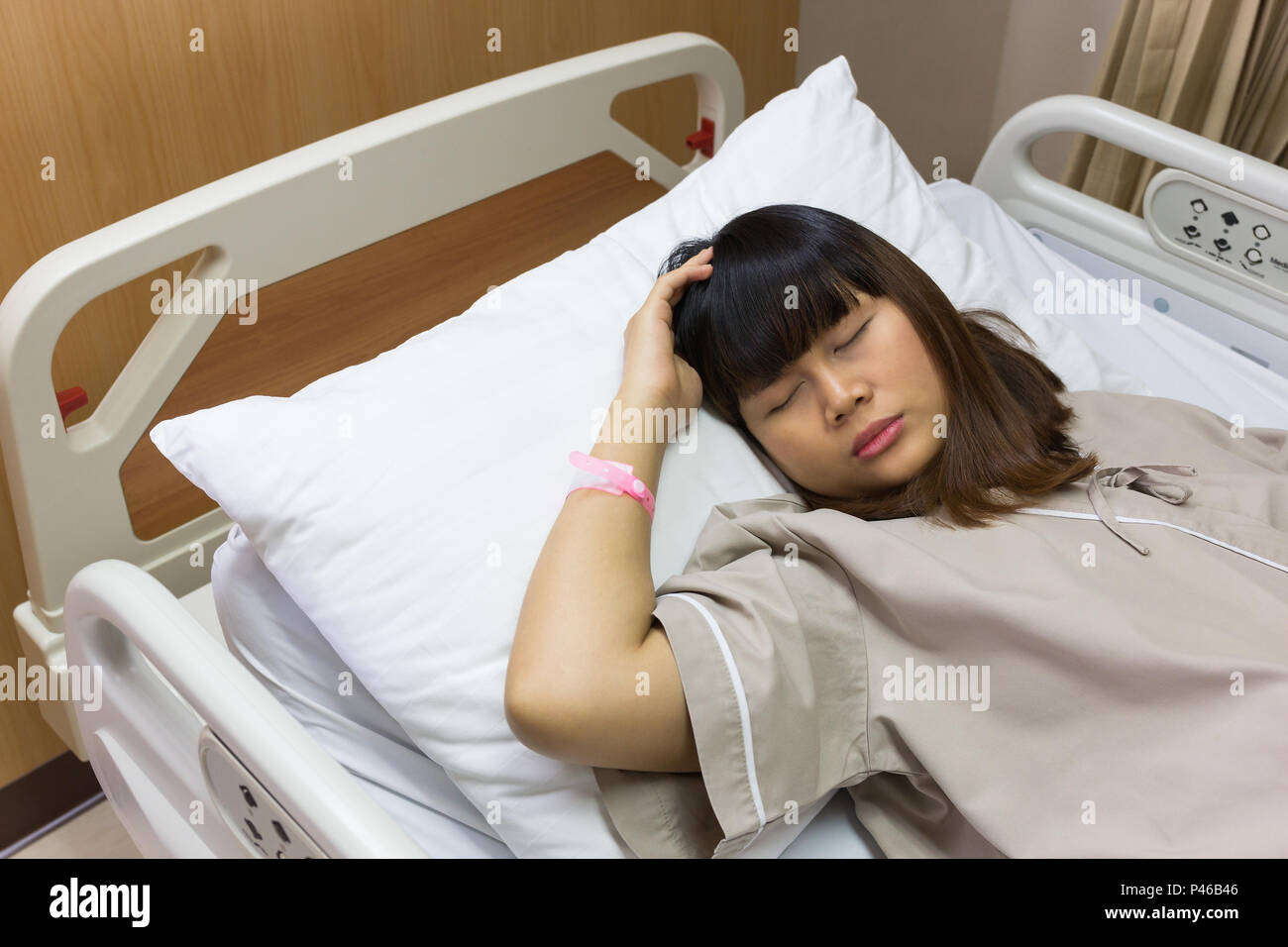 Schöne asiatische Patienten Frau Kopfschmerzen am Krankenbett bei der Luxus Zimmer Krankenhaus. Stockfoto