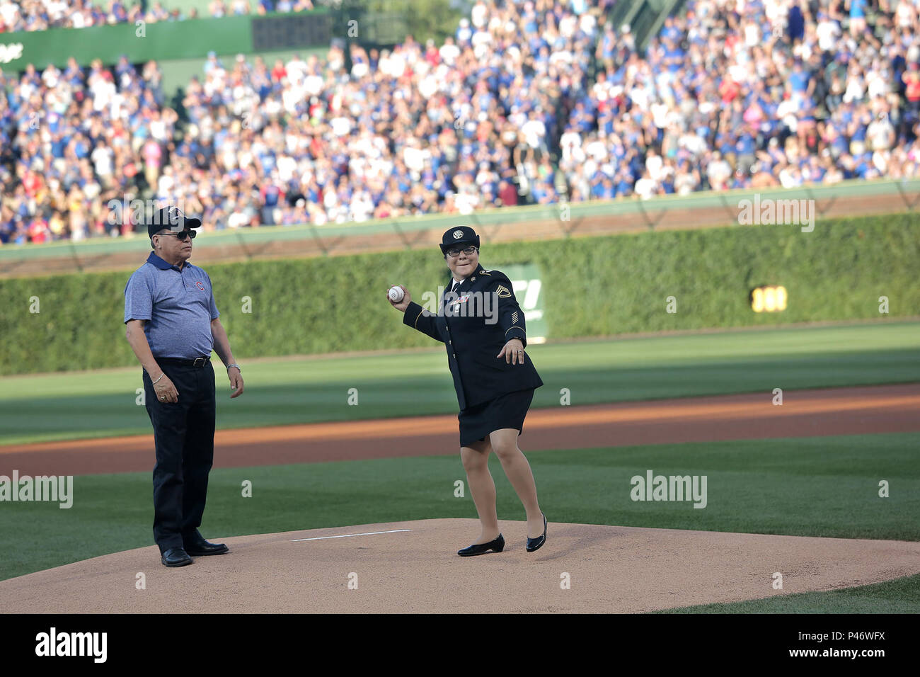 Armee finden Sgt. 1. Klasse Susan Torres wirft in einem zeremoniellen ersten Pitch, mit ihrem Vater, Richard Mejia, Vietnam Veteran und Purple Heart Empfänger, während eines Vaters Tag militärische Grüßen an der Chicago Cubs vs Pittsburgh Pirates Spiel bei Wrigley Field, 19. Juni 2016. Torres warf einen ersten Pitch und erkannt wurde, auf dem Feld, im vierten Inning, vor einem Publikum von mehr als 41.000. (U.S. Armee Foto von Sgt. 1. Klasse Anthony L.Taylor/Freigegeben) Stockfoto