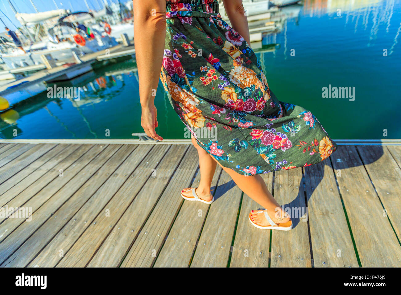 Detail der Beine der Frau zu Fuß auf hölzernen Steg der Marina de Lagos in Algarve, Portugal, Europa. Lifestyle Frau an der Bucht von Lagos in den Sommerferien. Stockfoto