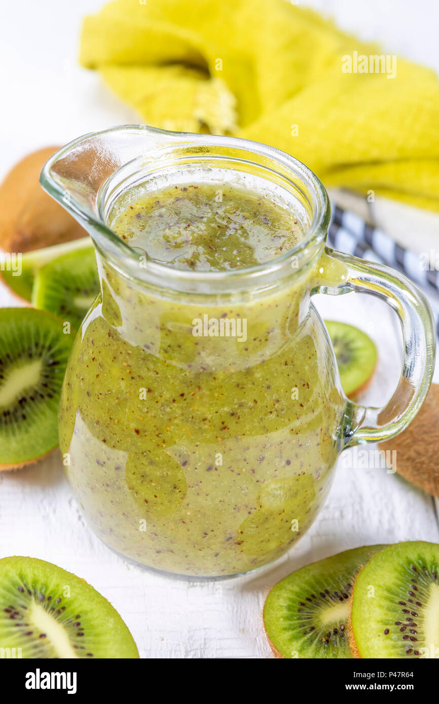 Gesunde, frische kiwi Smoothie in Glas auf einer hölzernen Hintergrund. Fokus auf kiwi Schicht in eine Karaffe. Stockfoto