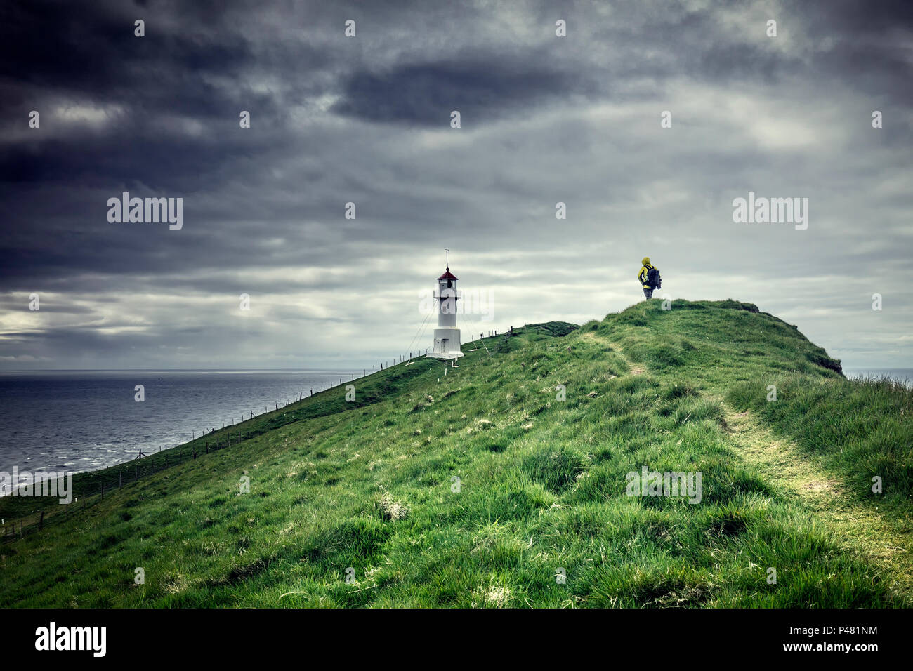 Fotograf mit gelben Regenmantel in mykines Färöer Stockfoto