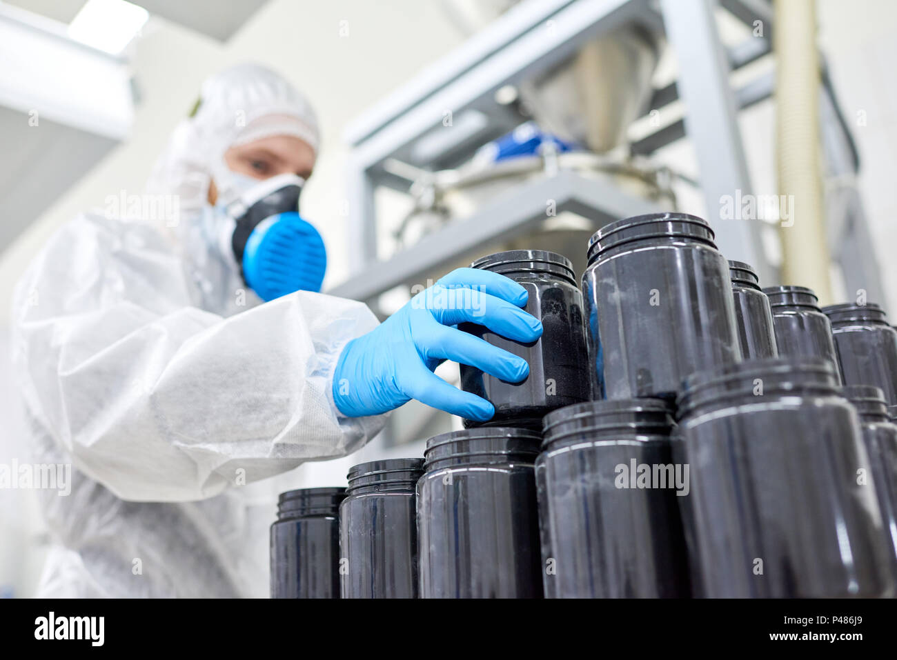 Ein Arbeiter, der Kunststoffbehälter von Stapel Stockfoto