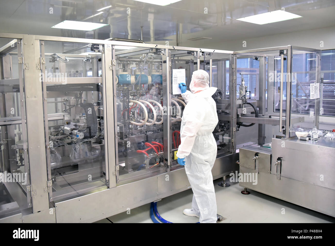Arbeitnehmer in sterilen Schutzkleidung in einem sauberen Zimmer eines pharamzie Unternehmen betreibt die technische Anlage zur Herstellung von Drogen Stockfoto