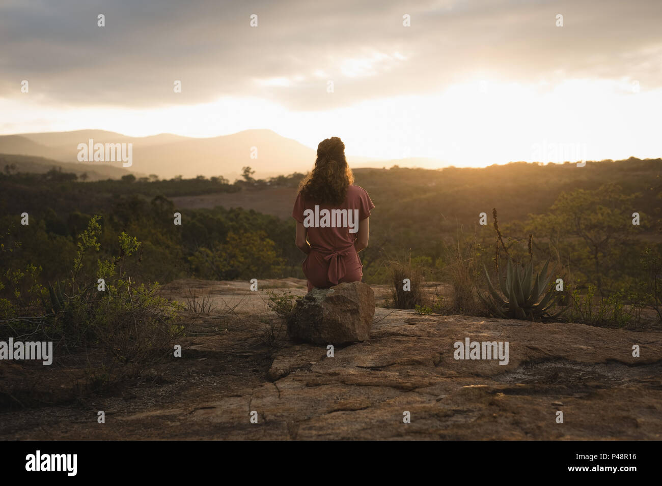 Frau sitzt auf Felsen und das Betrachten der Natur Stockfoto