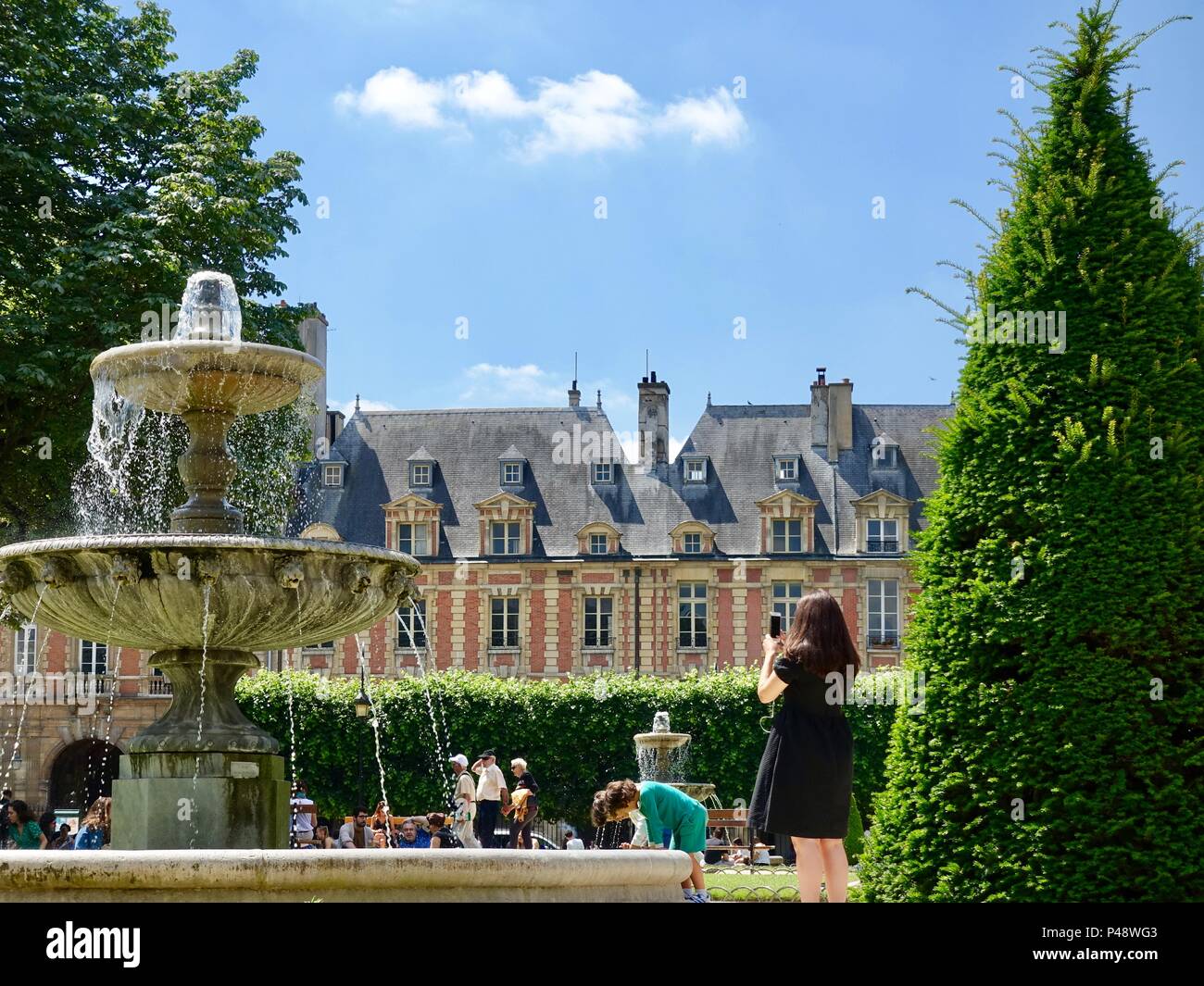 Menschen entspannend am Place des Vosges an einem warmen Juni Tag, Paris, Frankreich. Stockfoto