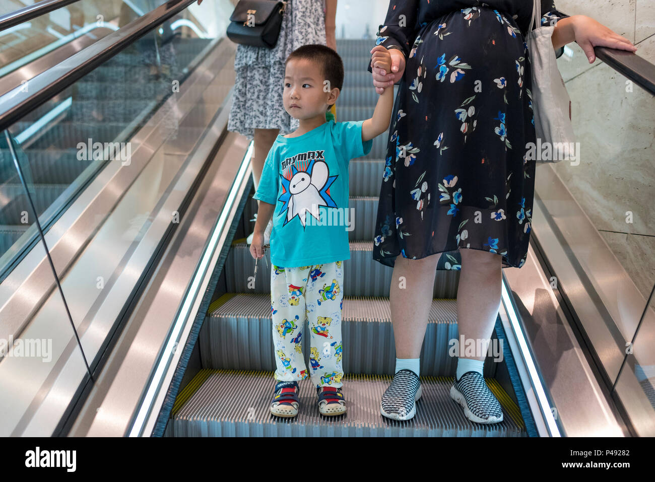 Schwangere Mutter und Sohn Fahrt mit der Rolltreppe in Stadtzentrum, Taian, Shandong Province, China Stockfoto