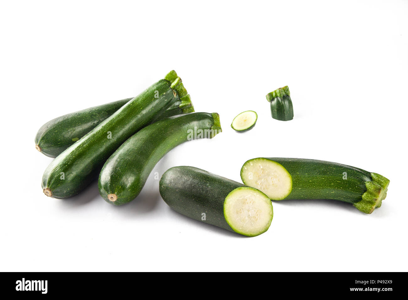 Drei Zucchini auf weißem Hintergrund und mit einem Schnitt in der Hälfte Stockfoto