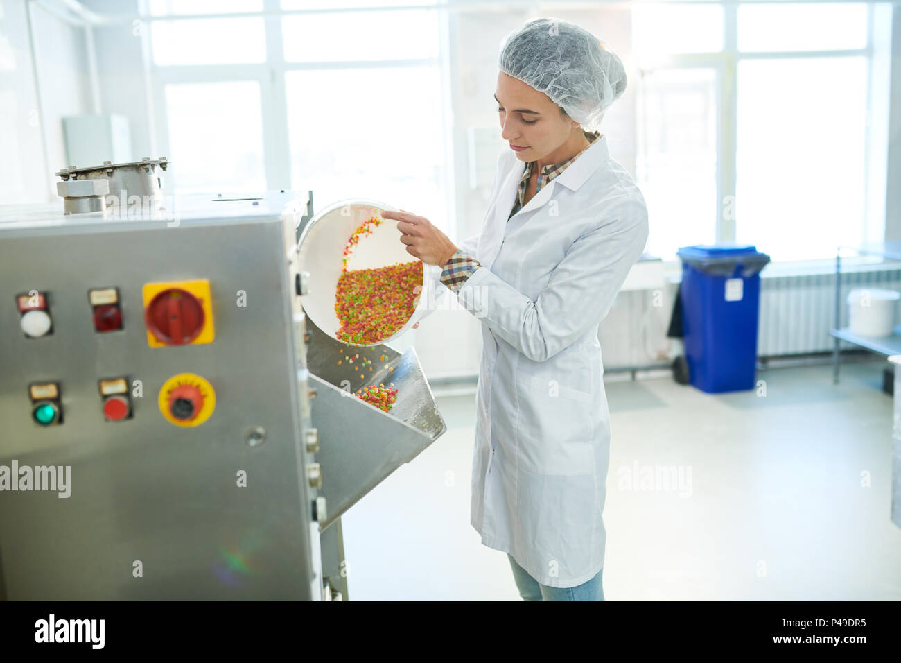 Süßwaren Fabrikarbeiter rainbow gießen Streuseln in Maschine Stockfoto