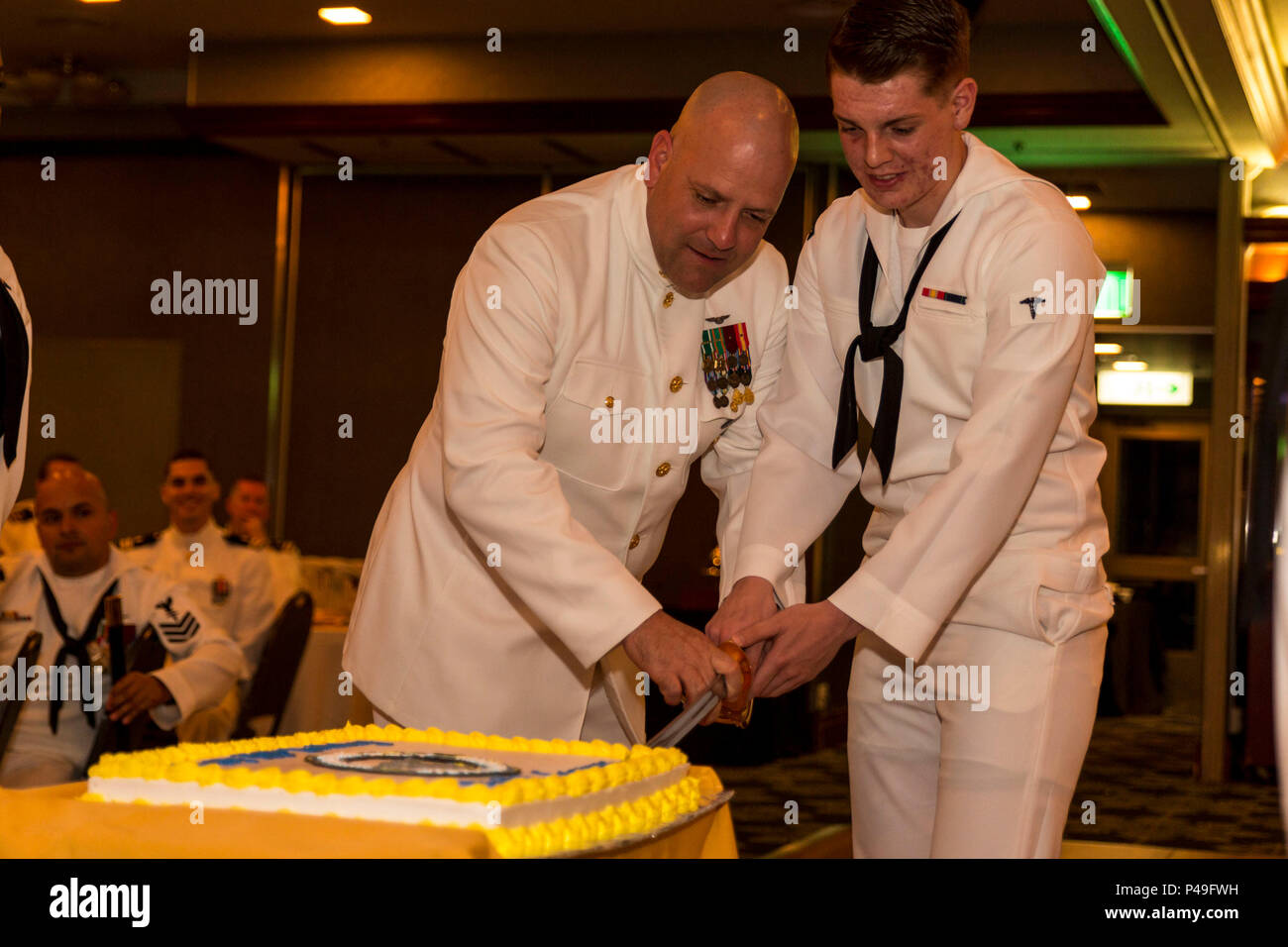 U.S. Navy Command Master Chief Petty Officer Daniel K. Feld, 1 Marine Flugzeugflügel command Master Chief, und Seaman Recruit Mitchel T. Bates, eine allgemeine Pflicht hallman mit der Robert M. Casey medizinische und zahnmedizinische Klinik, schneiden Sie einen zeremoniellen Kuchen während der 118 Hospital Corpsman Kugel an der Marine Corps Air Station Iwakuni, Japan, 18. Juni 2016. Durch Tradition, dem ältesten und jüngsten Segler aus der Befehl Ausschneiden der zeremoniellen Kuchen. (U.S. Marine Corps Foto von Lance Cpl. Aaron Henson/Freigegeben) Stockfoto