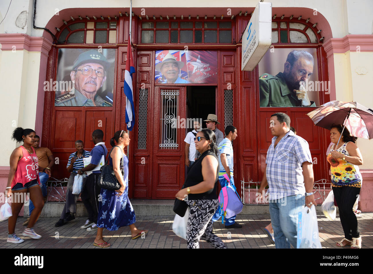 SANTIAGO DE CUBA, Kuba - 29. NOVEMBER 2016: Kubaner auf Santiago de Cuba Straßen auf die Schränke Porträts von Fidel und Raul Castro suchen Stockfoto