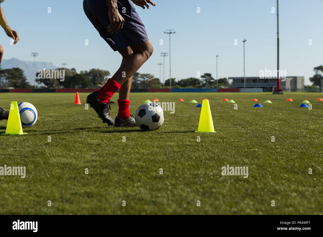 Fußballspieler dribbeln den Ball durch Kegel Stockfoto