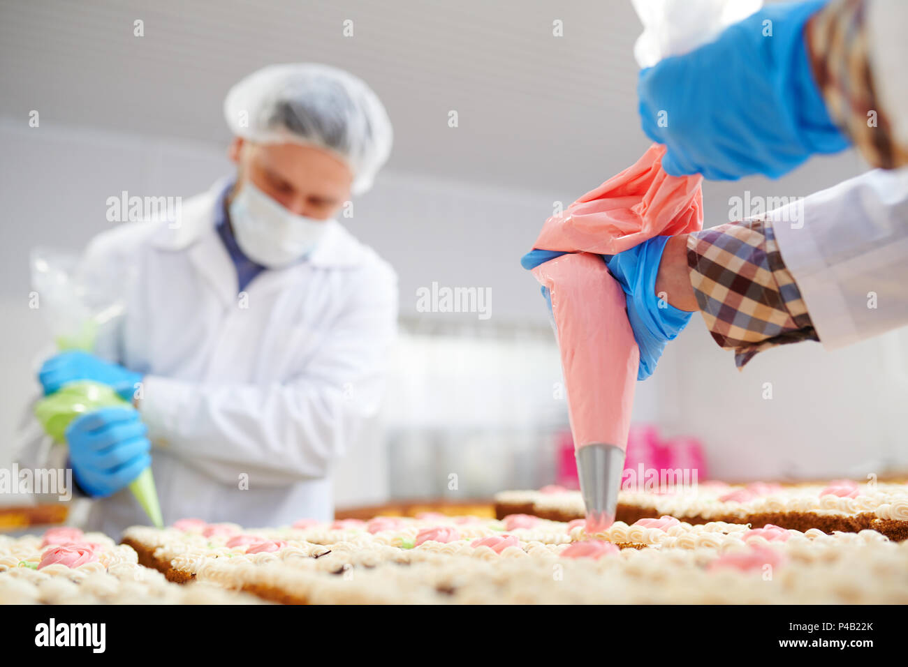 Professionelle Bäcker dekorieren Kuchen mit Sahne Stockfoto