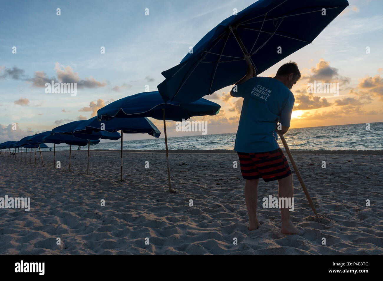 Hotel Strand Attendant stellt Sonnenschirm wie Sonne auf der Atlantischen Ozean in Miami Beach, Florida Stockfoto