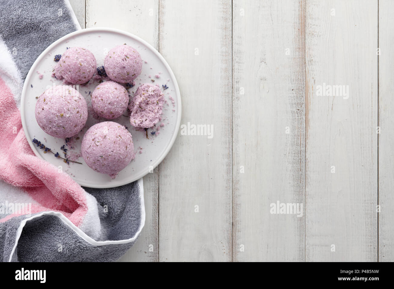 Handgefertigte Lavendel Bad Bomben mit Handtuch auf weißen Planken Stockfoto