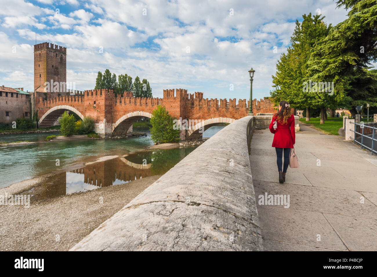 Frau Wandern am Flussufer in Verona. Castelvecchio Brücke im Hintergrund. Verona, Venetien, Italien Stockfoto