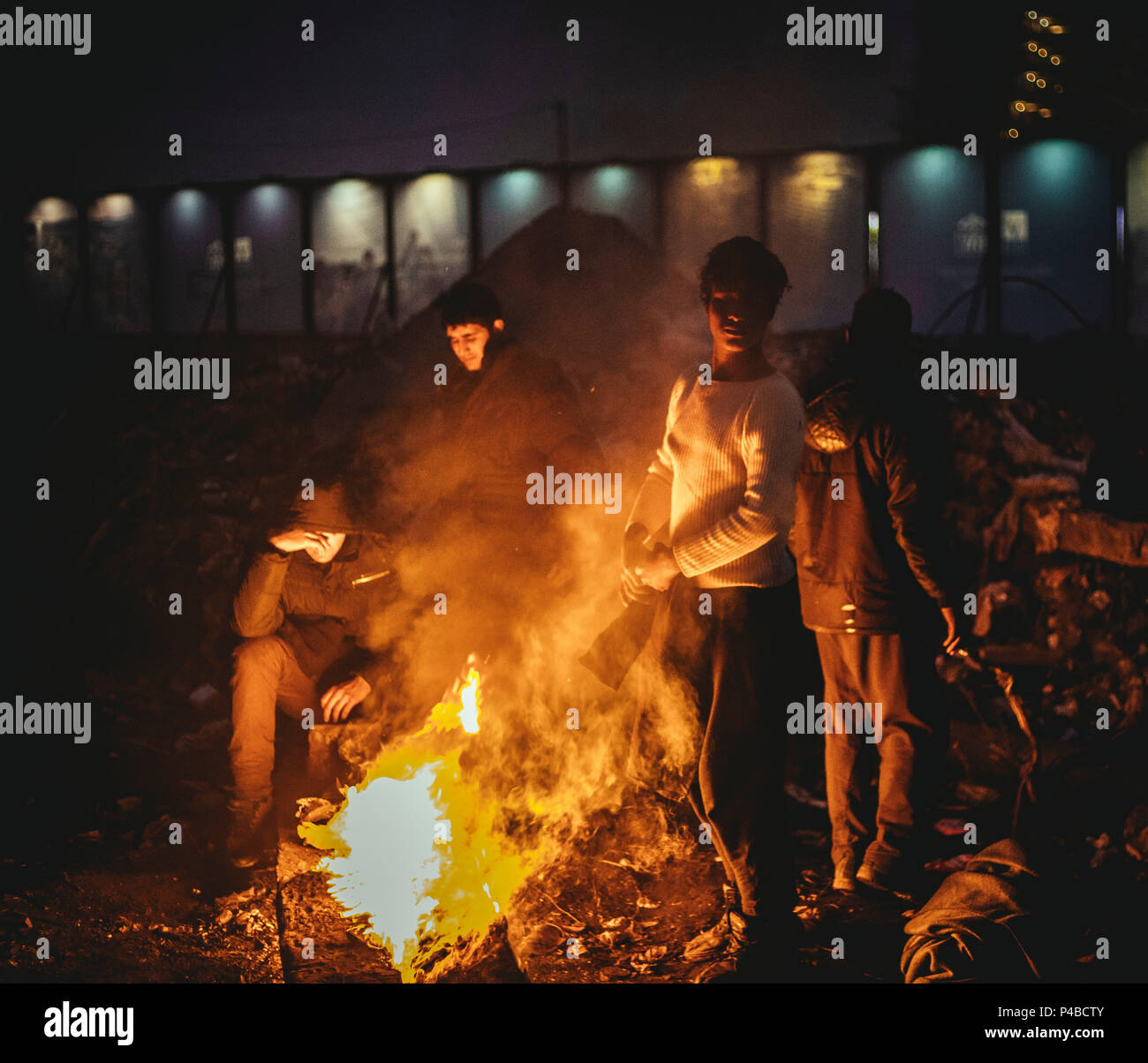 Lagerkomplex in Belgrad, Serbien. Im März ist die Zahl der Flüchtlinge, vor allem aus Afghanistan und Pakistan ist steigend. Immer mehr Kinder und Jugendliche kommen. Freiwillige aus verschiedenen Ländern organisieren Projekte in und um das Lagerhaus Komplex, Bereitstellung von Nahrungsmitteln und Kleidung und Brennholz und Workshops. In den letzten Monaten eine ordnungsgemäße Infrastruktur der Solidarität hat in diesem Bereich im Herzen von Belgrad gewachsen. Flüchtlinge stehen rund um ein Lagerfeuer. Stockfoto