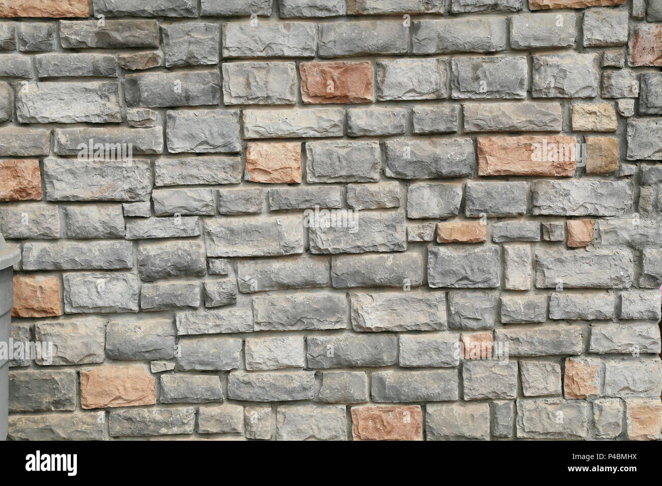 Rustische Mauer aus Naturstein mit gemischten grauen und braunen unregelmäßigen Steinblöcken Stockfoto
