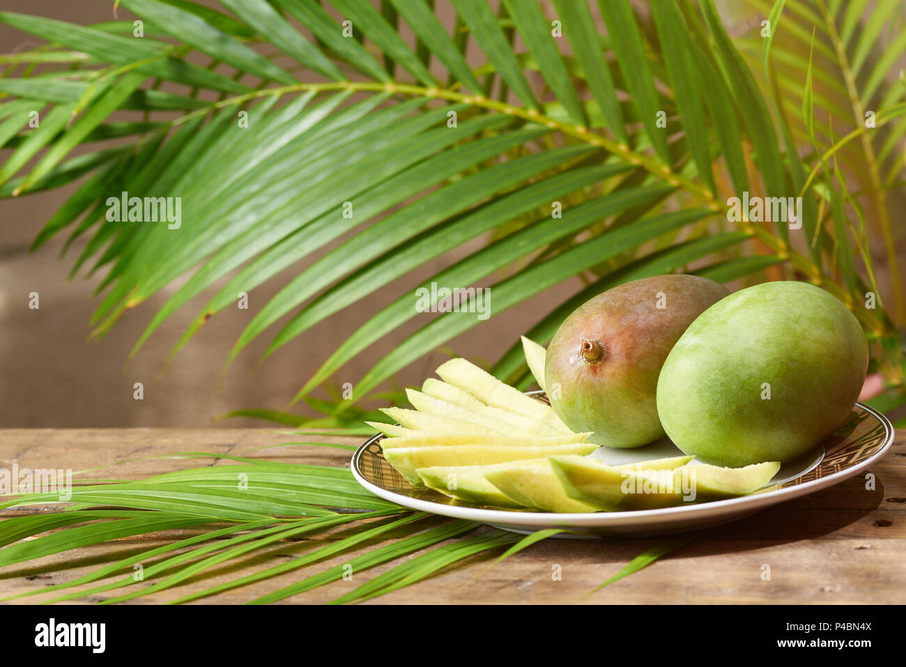 Mango Obst auf Platte mit sonnigen grünen Hintergrund in Scheiben geschnitten Stockfoto