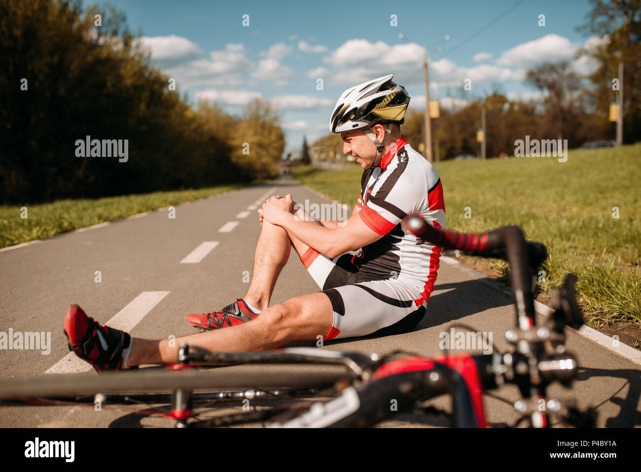 Männliche bycyclist fiel aus Fahrrad und schlug seine Knie Stockfoto