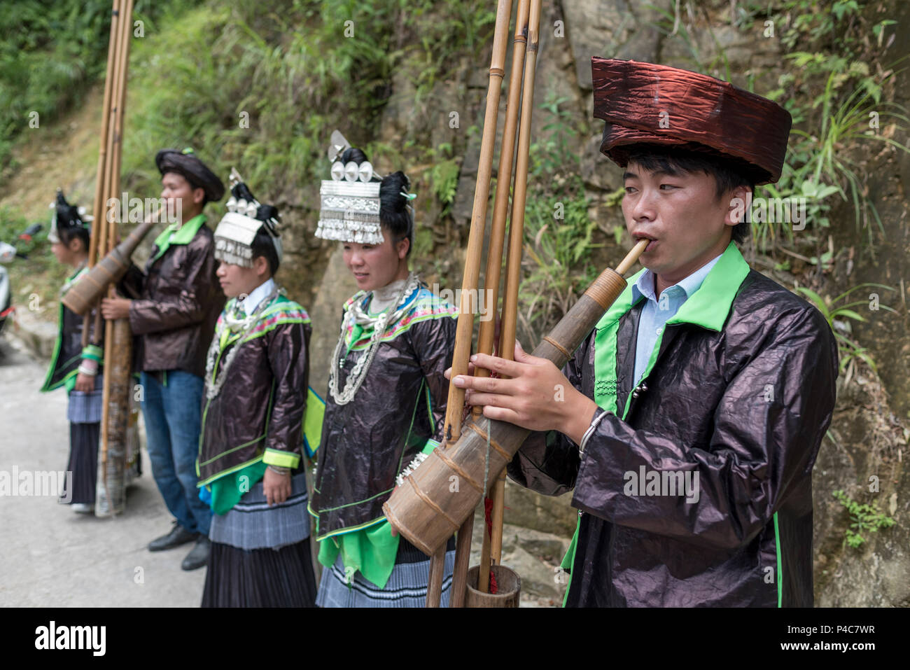 Sänger mit großen silbernen Haar Stücke und Musiker Bambus Blasinstrumente bei Feier, Xiaoao Miao athnis Stockfoto