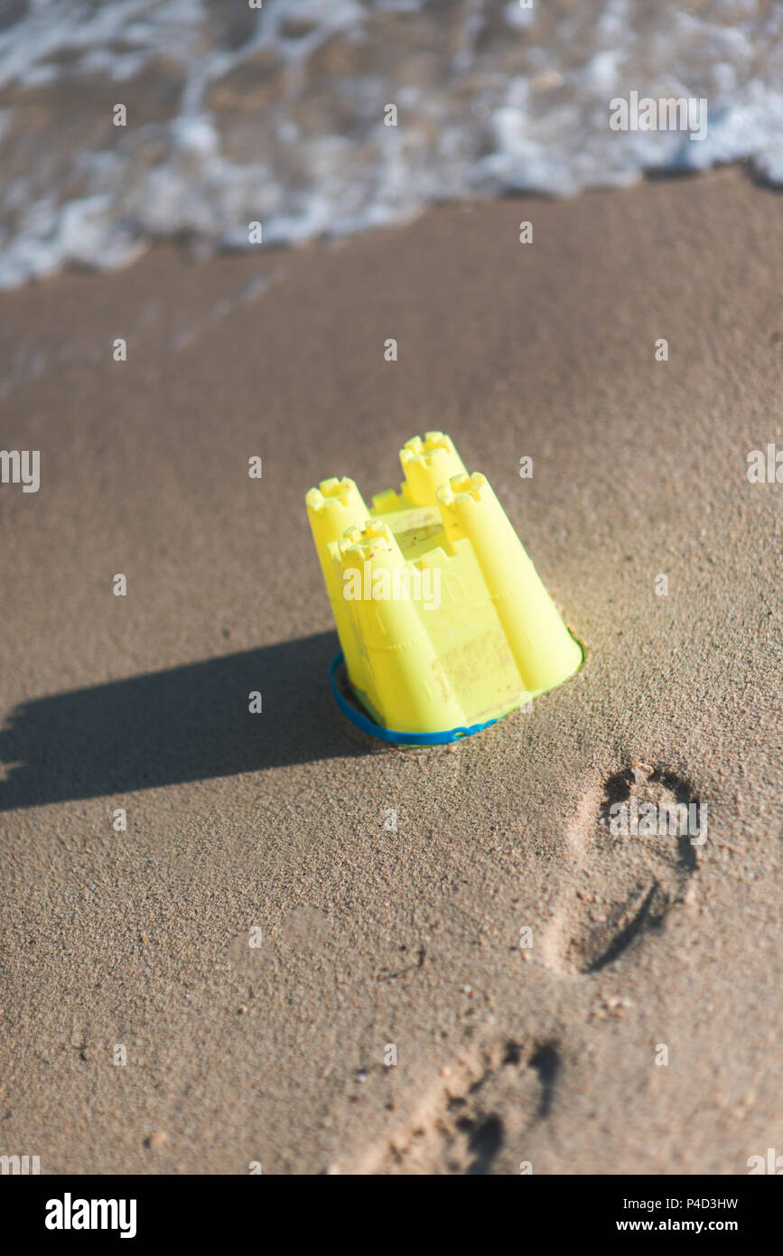 Kleine aber schöne Sandburg am Strand mit etwas Spielzeug und eine Schaufel aus Kunststoff Stockfoto