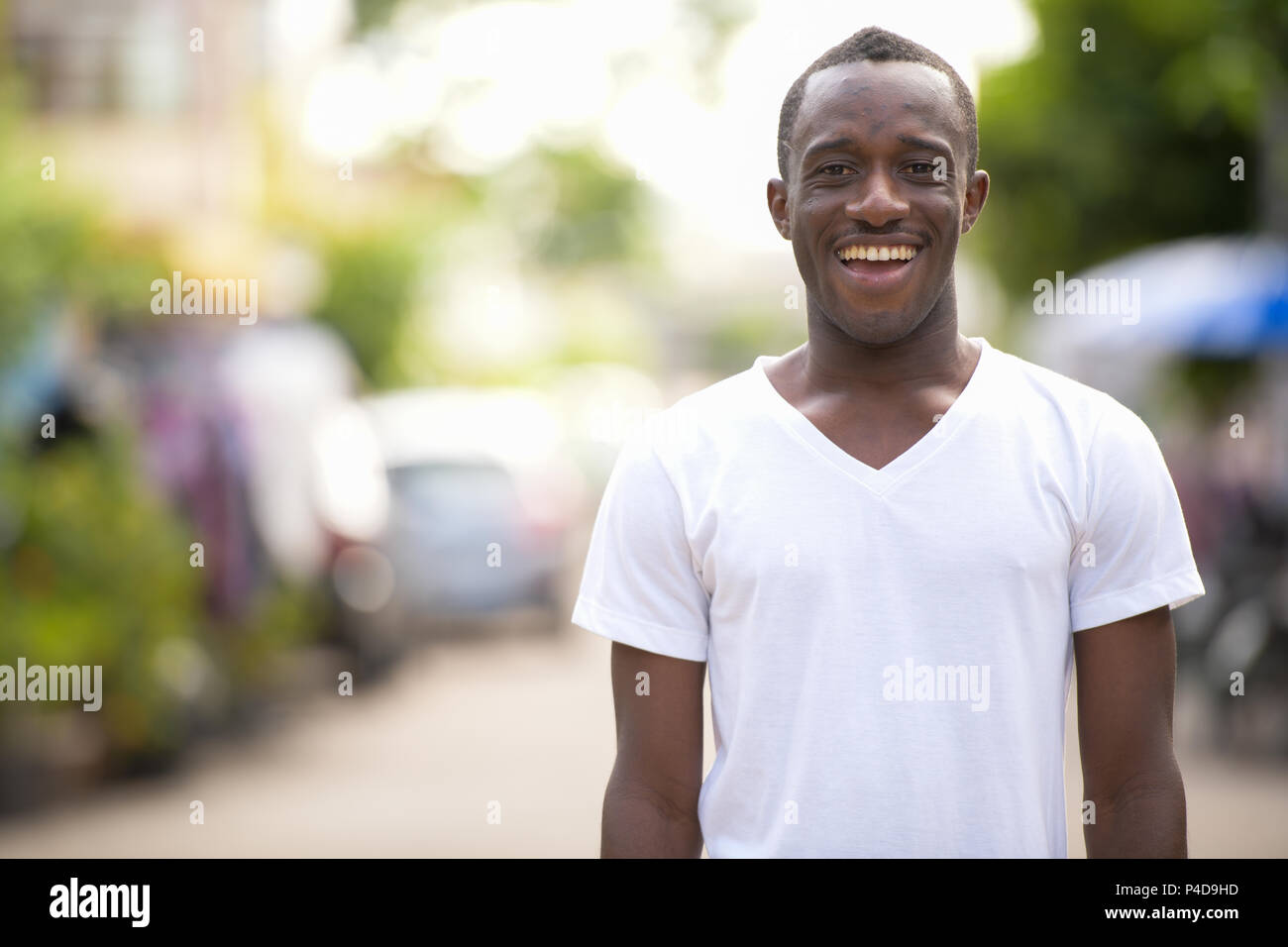 Junge glücklich afrikanischer Mann in den Straßen lächelnd im Freien Stockfoto