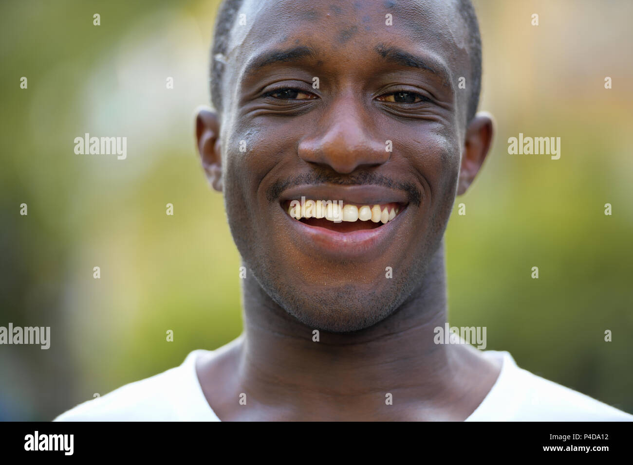 Junge glücklich afrikanischer Mann in den Straßen lächelnd im Freien Stockfoto