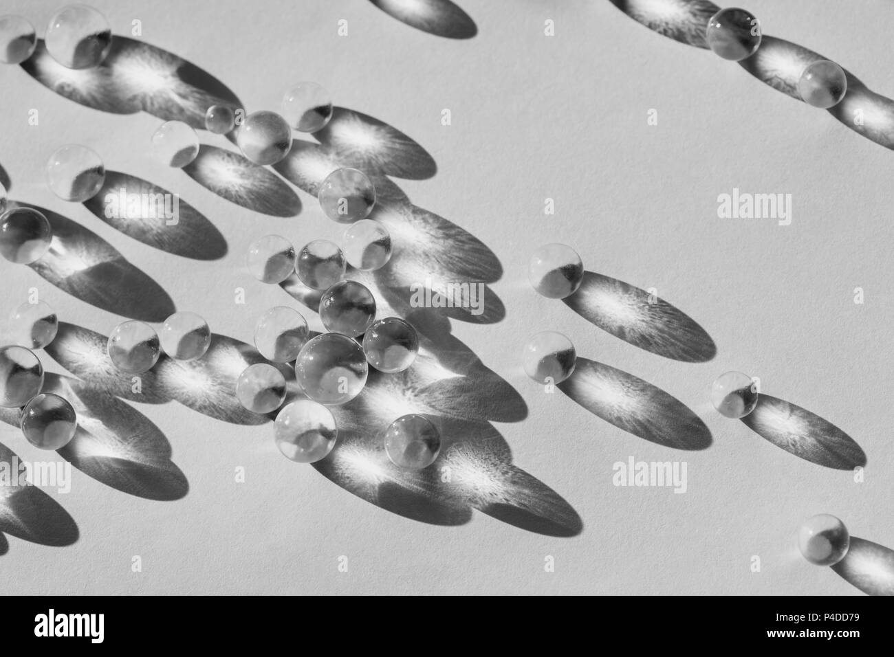Kleine Glaskugeln in direktem Sonnenlicht, Makro. Zusammenfassung Hintergrund, Schwarz und Weiß Foto Stockfoto