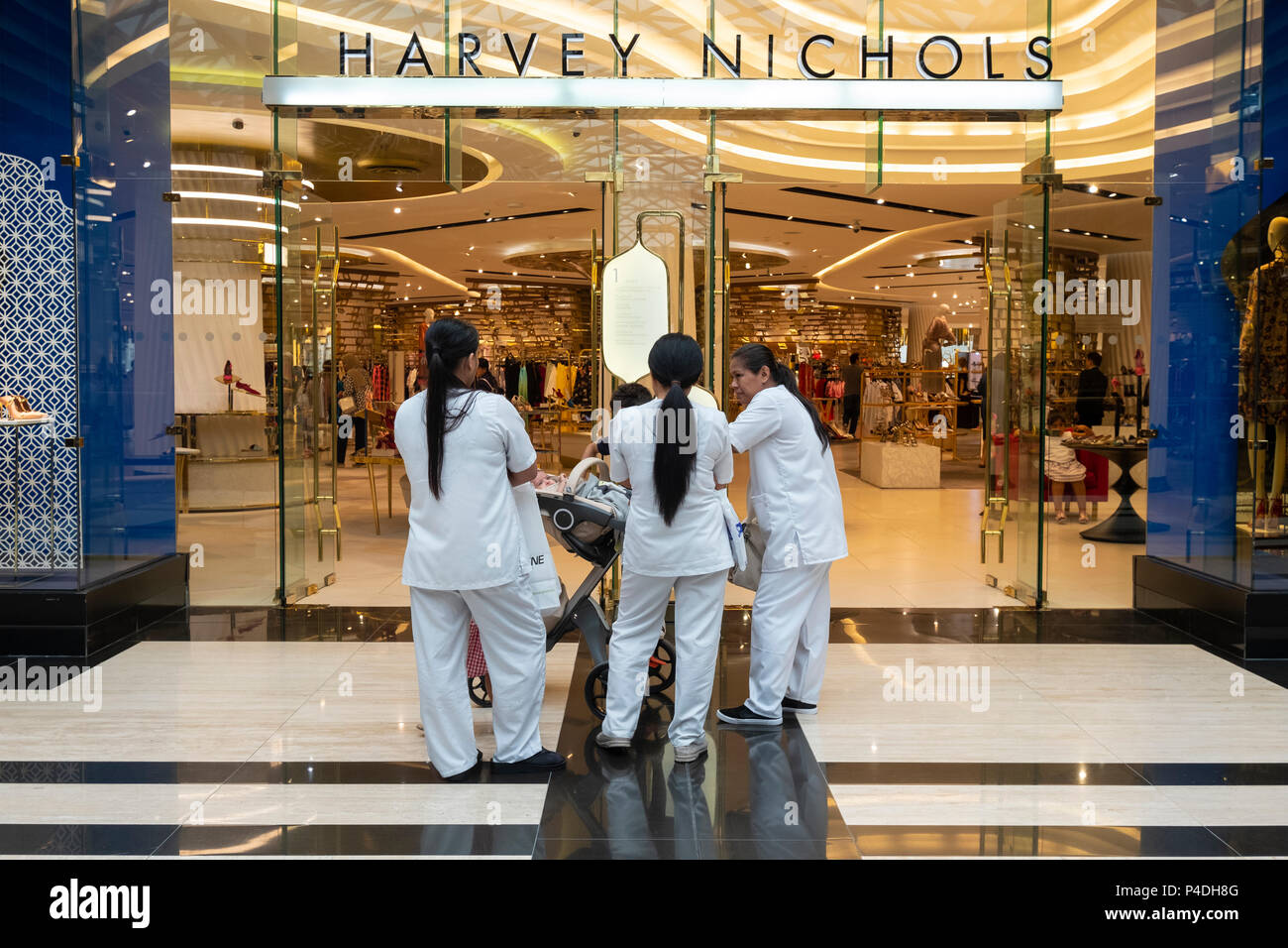 Weibliche Zimmermädchen warten draußen Harvey Nichols in der Prestige Mall innerhalb der Avenues Shopping Mall in Kuwait City, Kuwait. Stockfoto