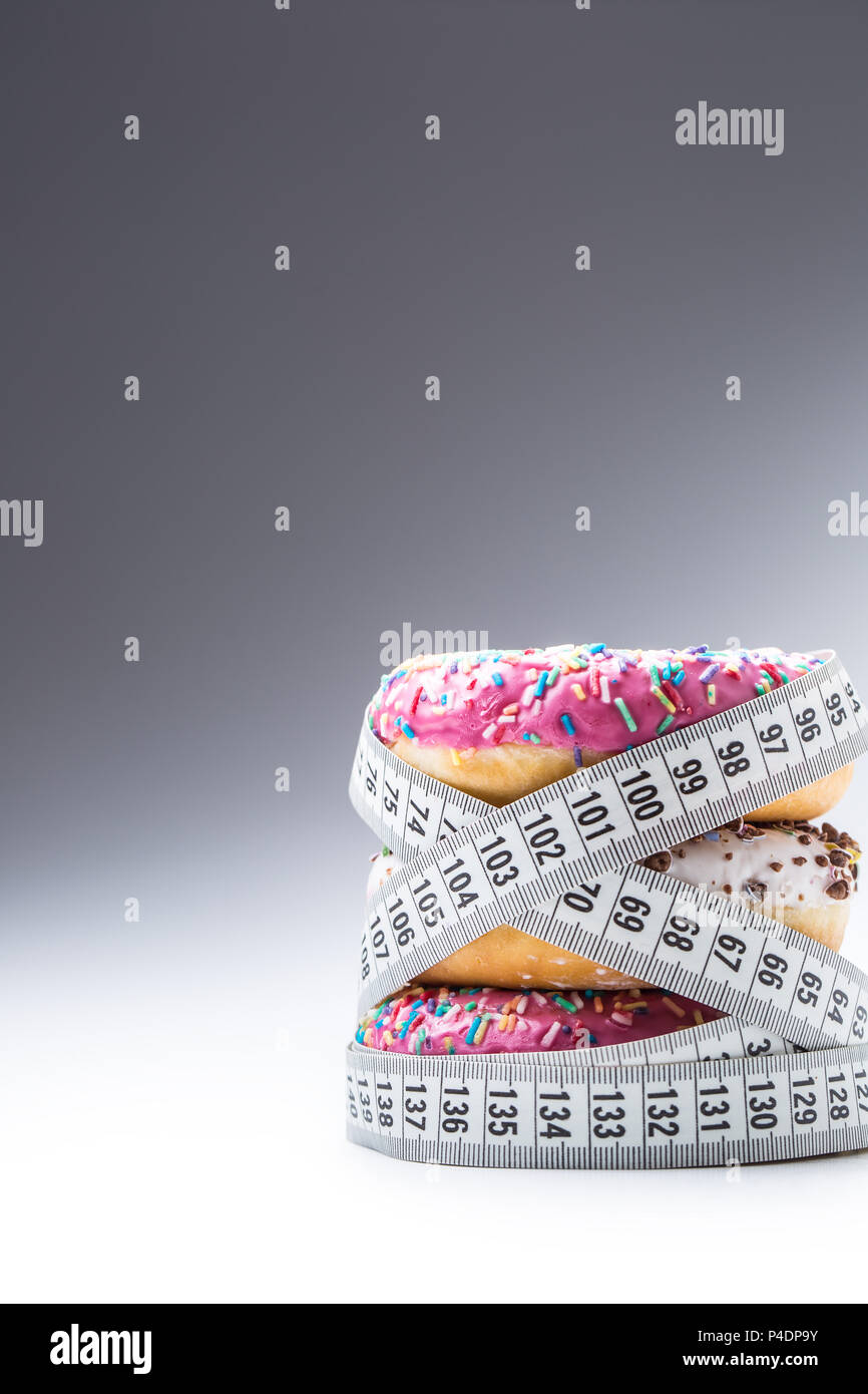 Drei bunte Donuts in einen Schneider Massband umwickelt. Stockfoto